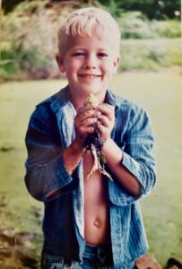 boy holding a frog and showing it to his mother